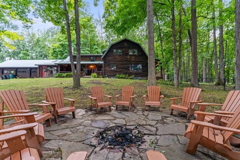 Gather around the fire pit under towering trees, complete with Adirondack chairs and a serene view of the lake in the distance.