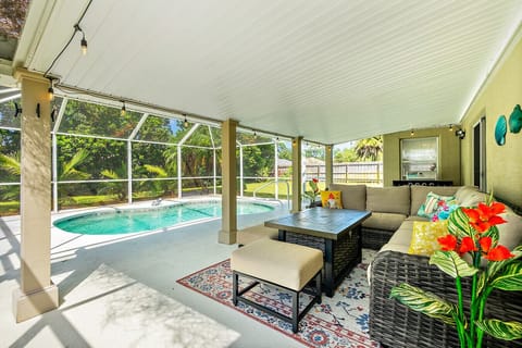 Screened-in poolside patio with comfy sectional seating, table, and tropical views perfect for relaxing outdoors in comfort and privacy.