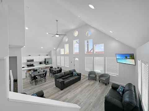 Open great room with soaring vaulted ceiling, dining, and kitchen in one bright space