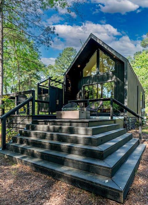 Modern A-frame style cabin featuring a private deck and forest surroundings.