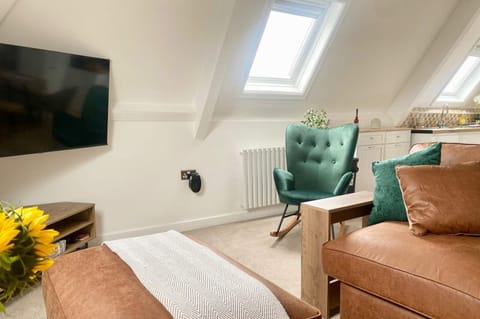 Bright, loft-style living space with skylights, comfy seating, and a smart TV — ideal for cosy evenings in.