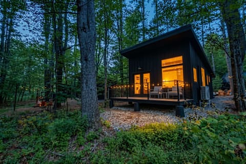 The cabin features a large deck overlooking the woods with comfortable patio furniture