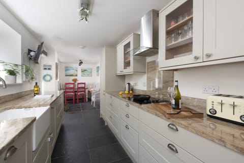 Kitchen with toaster, hob, sink and small dining table - Trevethen Cottage