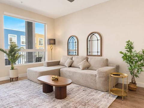 Spacious living room featuring a cozy L-shaped sofa, a full-size air mattress, and a 65" Smart TV with preloaded access to Netflix, Hulu, and Disney+, all set up for your enjoyment.