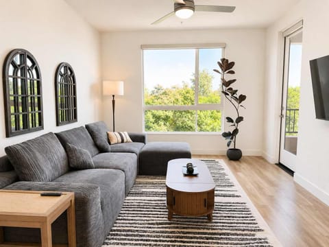 Spacious living room featuring a cozy L-shaped sofa, a full-size air mattress, and a 65" Smart TV with preloaded access to Netflix, Hulu, and Disney+, all set up for your enjoyment.