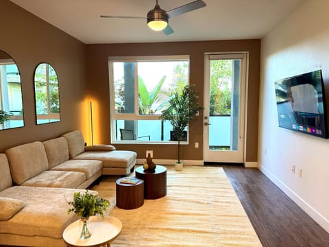 Spacious living room featuring a cozy L-shaped sofa, a full-size air mattress, and a 65" Smart TV with preloaded access to Netflix, Hulu, and Disney+, all set up for your enjoyment.