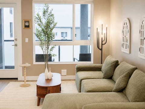Spacious living room featuring a cozy L-shaped sofa, a full-size air mattress, and a 65" Smart TV with preloaded access to Netflix, Hulu, and Disney+, all set up for your enjoyment.
