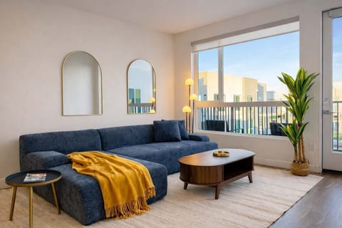 Spacious living room featuring a cozy L-shaped sofa, a full-size air mattress, and a 65" Smart TV with preloaded access to Netflix, Hulu, and Disney+, all set up for your enjoyment.