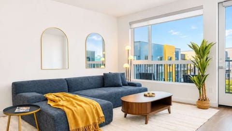 Spacious living room featuring a cozy L-shaped sofa, a full-size air mattress, and a 65" Smart TV with preloaded access to Netflix, Hulu, and Disney+, all set up for your enjoyment.