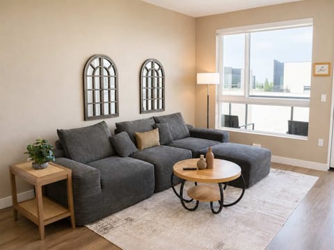 Spacious living room featuring a cozy L-shaped sofa, a full-size air mattress, and a 65" Smart TV with preloaded access to Netflix, Hulu, and Disney+, all set up for your enjoyment.