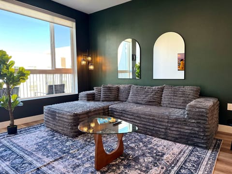 Spacious living room featuring a cozy L-shaped sofa, a full-size air mattress, and a 65" Smart TV with preloaded access to Netflix, Hulu, and Disney+, all set up for your enjoyment.