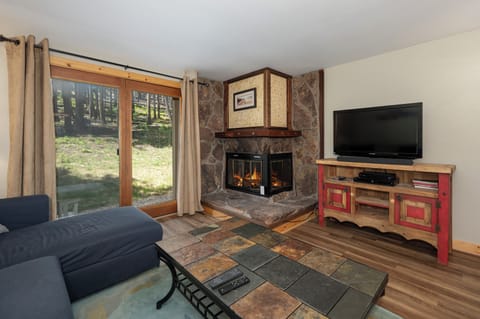 Cozy up by your crackling stone fireplace while watching TV, with serene forest views through your patio doors creating the perfect mountain retreat.