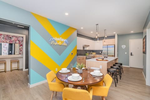 Dining area with comfy seating for four and a bold neon sign that brings the Nashville vibe to life.