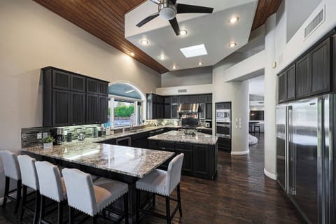 Whether you're cooking, sipping wine, or chatting with guests, this open-concept layout with bar seating, double ovens, and statement lighting is designed for effortless entertaining.