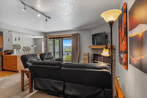 Unwind in your stylish living room with cozy leather seating, warm fireplace, and stunning mountain views from your private balcony.