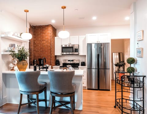 Stylish kitchen with brick accent, modern appliances, and a cozy breakfast bar.