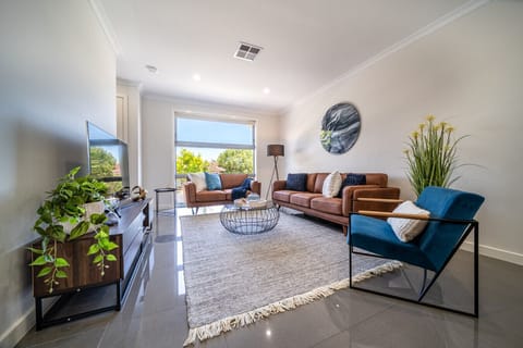 Unwind in the sunlit living area, where plush seating and soft textures create an inviting space to relax.