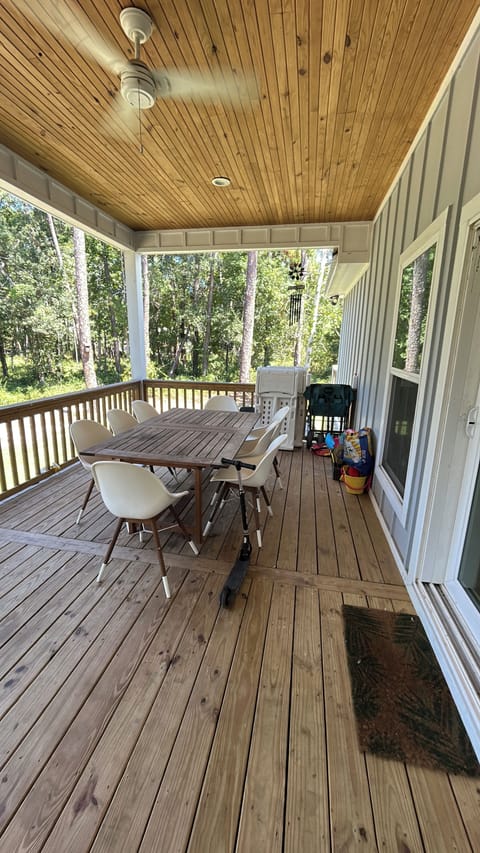 Back deck with outdoor dining, charcoal smoker, and beach supplies