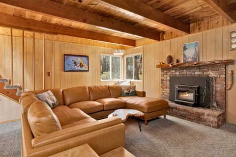 Cozy mountain living room with a stone fireplace, comfy seating, and smart TV—perfect for relaxing evenings, movie nights, and warm cabin vibes after outdoor adventures.