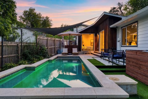 Private pool with mid-century modern home at sunset.