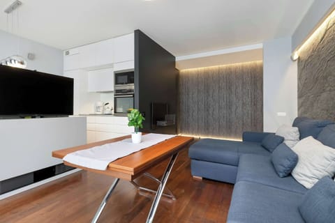 Another angle of the living area with a mounted TV, sleek furniture, and potted plants. The open-plan layout feels bright and welcoming.