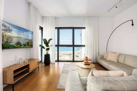 Sunlit living room frames shimmering sea views, creating a spacious retreat moments from beachside cafes.