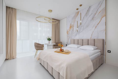 Sleeping area with a large comfortable bed, marble-effect wall design, and elegant golden accents.