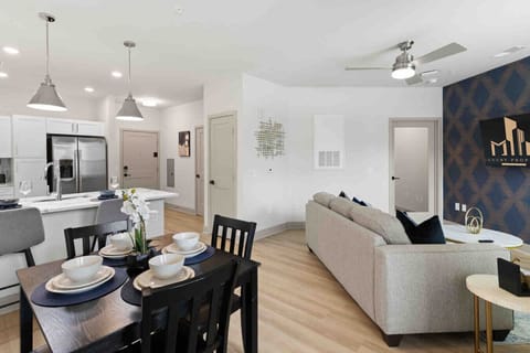 Dining & Living Area-Inviting open layout with dining table set for four, cozy sofa, and modern kitchen with stainless steel appliances. Perfect for meals, relaxation, and entertaining.