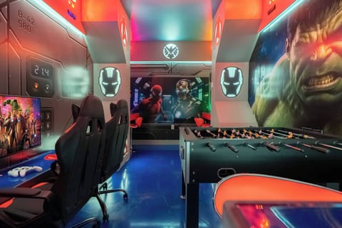 Discover our vibrant game room, featuring sleek gaming chairs and a foosball table for friendly competition. With dynamic lighting and striking superhero murals, it's the ideal spot to relax after a day of adventure.