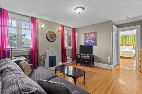 Bright Living Room with Decorative Fireplace.  Enjoy the sun-drenched lounge featuring a stylish decorative fireplace, hardwood floors, and vibrant decor—perfect for a relaxing stay.