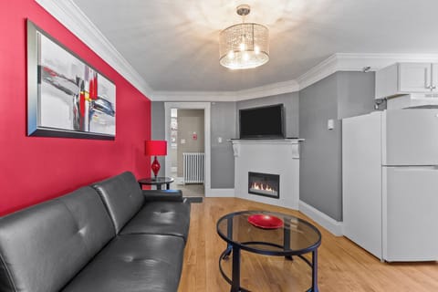 Cozy living area with a red accent wall, leather sofa, fireplace, and TV for movie nights.