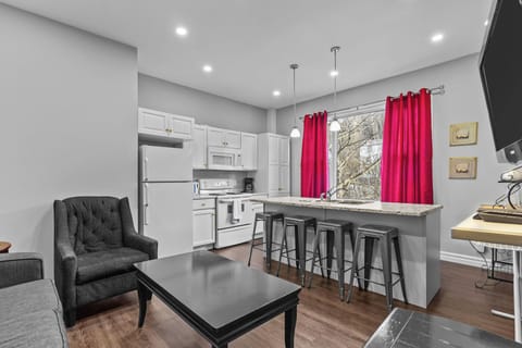 Modern Kitchen: Bright, open-concept kitchen featuring white cabinetry, full-sized appliances, and a large breakfast bar with seating for four.