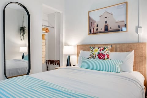 A tranquil sleeping area with decorative artwork and a generous mirror.


