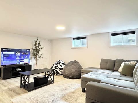 Détendez-vous avec style grâce à un sectionnel élégant, des poufs poires et une télévision intelligente pour vous divertir!