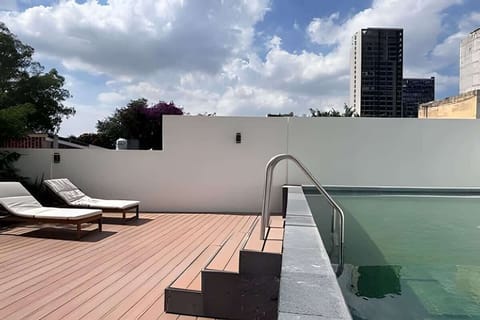 Shared rooftop pool deck w/ loungers & city views, perfect for soaking up the sun