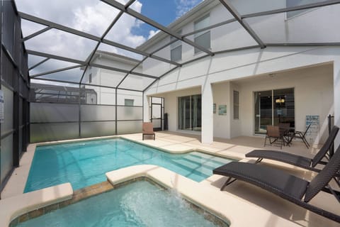 Welcome to your private oasis, featuring a sparkling pool perfect for unwinding under the sun. Enjoy relaxation on sleek loungers, all within a screened enclosure that offers a refreshing breeze without any interruptions.