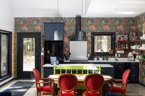 Striking kitchen w/ patterned walls, dark cabinetry, & island seating for gathering.