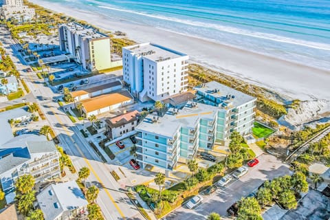 Aerial view of the beachfront condo building, ideally located just steps from the sand with direct beach access, surrounding palm trees, and nearby parking.