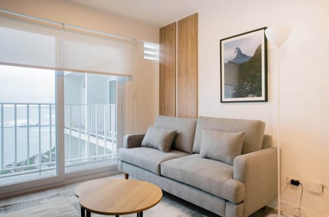 Living room with balcony access – features a grey sofa, round coffee table, and a wall-mounted artwork.