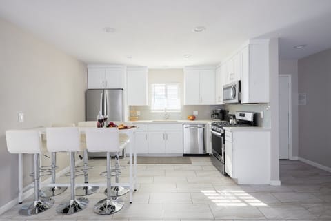 Bright kitchen with white cabinets and countertops, stainless steel appliances, and a dining table with seating for six.