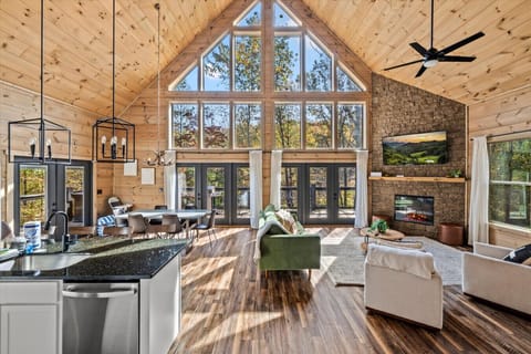 Sunlight pours through the wall of windows, filling the open living space with warmth, mountain views, and the perfect cabin glow.