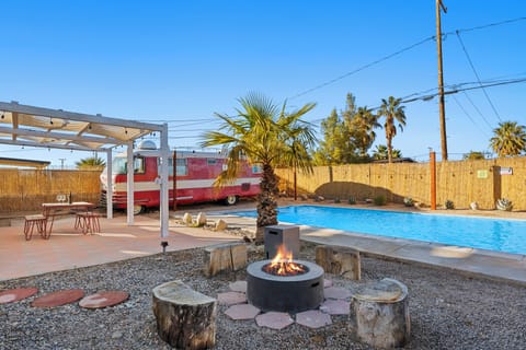 Backyard oasis with pool, hot tub, al fresco dining, and firepit with classic RV vibes.