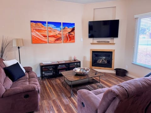 Cozy living room with two couches, a smart tv, gas fireplace, and games.