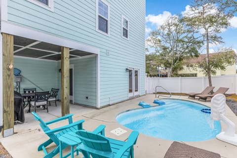 Pool area with lounge chairs, a basketball hoop for kids, and a dining area with a grill.
