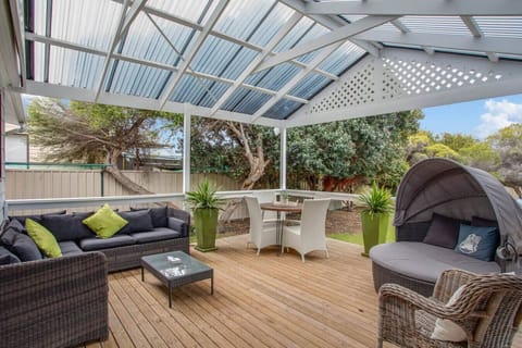 Unwind on the covered deck with comfortable outdoor seating, a dining area, and BBQ facilities — the ideal spot for sunset drinks or lazy lunches overlooking the lush backyard.