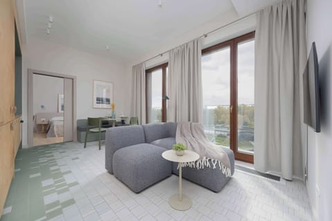 The bright living room with large windows and access to the balcony invites you to relax, offering beautiful natural light and a comfortable lounge area.