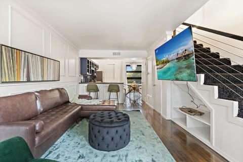 The spacious living room boasts an inviting open-concept design, with a massive Smart TV and comfortable sofa and chair, serving as the focal point for both relaxation and entertainment. French doors lead out to your private patio. 
