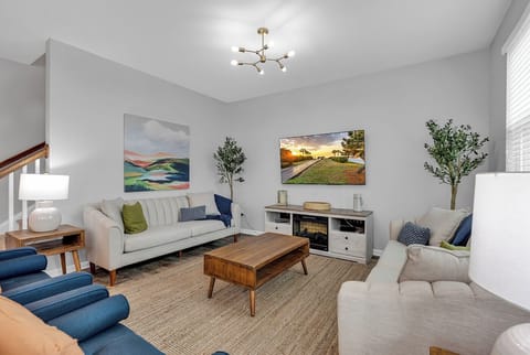 Cozy living room with natural light, comfy seating, and a smart TV for relaxing.