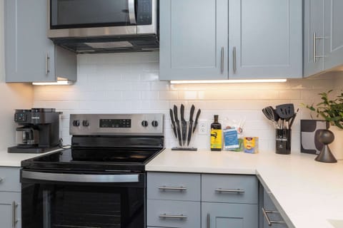 Compact kitchen fully stocked with all essentials and sleek stainless steel appliances—everything you need in a cozy space.