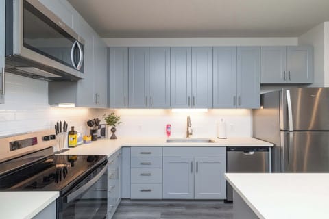 Compact kitchen fully stocked with all essentials and sleek stainless steel appliances—everything you need in a cozy space.